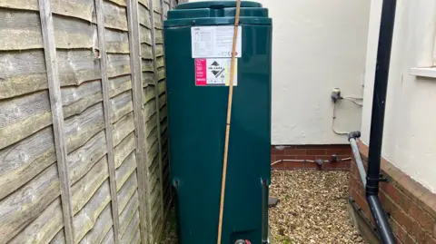 A large green oil tank in a garden.