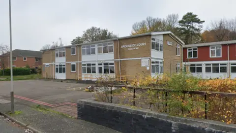 A two storey care home site with a car park in front