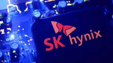 A screen displaying the SK Hynix logo posed above a computing motherboard