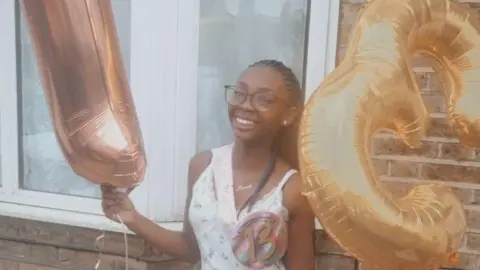 LEIGH DAY A smiling Hannah Jacobs holding birthday balloons 