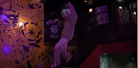 Justin Bieber A man slides down a banister in a darkly-lit pub