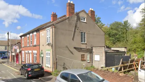 A residential property on Woden Road, Heath Town, Wolverhampton with two cars, a silver one and a black one, parked on the curb. 