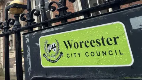 LDRS A sign at Worcester City Hall for the city council. The green sign has raindrops on it and is attached to black metal railings.