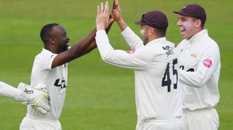 Surrey players celebrate a  Kemar Roach wicket