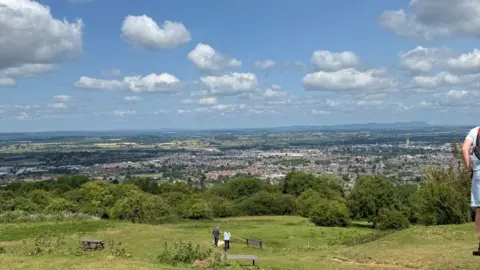 A shot of Gloucester from the top of Robinswood Hill with some people admiring the view. 