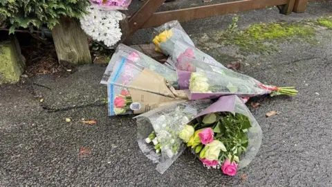Bunches of flowers on the floor outside a gate 