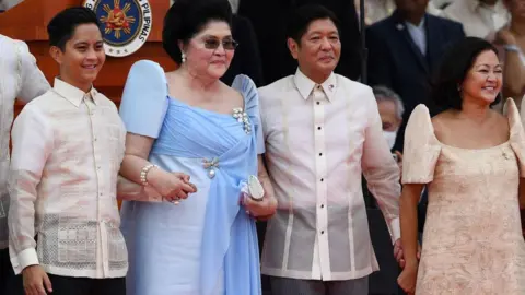 Getty Images Former first lady Imelda Marcos (2nd L) holds hands with her son, the new Philippine President Ferdinand Marcos Jr. (2nd R), as they stand with family members after he took his oath of office, during the inauguration ceremony at the National Museum in Manila on June 30, 2022.