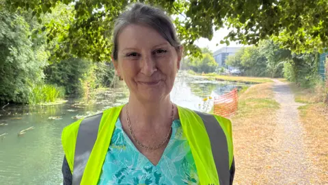 Stacey Reynolds, a woman standing by the canal in a hi-vis jacket.