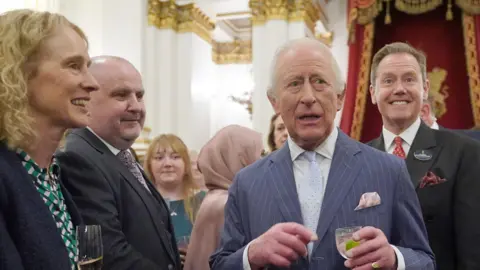 PA Media King Charles during a reception. Belinda Bradley is in the background. Other attendees are also gathered around the King.