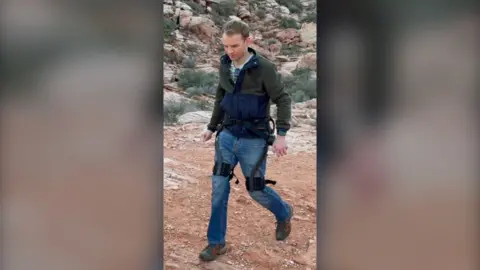 A man wears an exoskeleton in an arid landscape