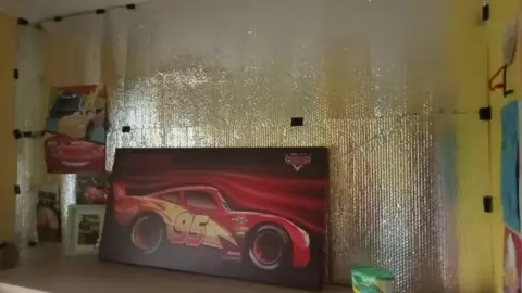 Kathrina Kirk A section of wall is visible which has been covered in a large foil wrap.
A poster of Lighting McQueen from Disney's Cars is seen on a poster.
