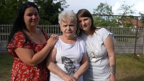 Two young women and their grandmother look at the camera