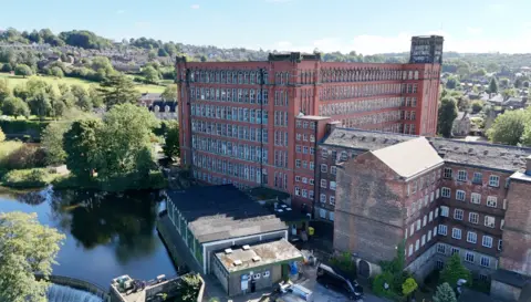 The picture shows an aerial view of the old Belper Mills buildings. The construction is red bricks and there are many windows on each floor