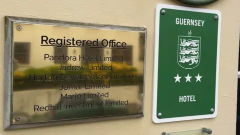 A gold wall plaque that shows the hotel is a registered office and next to it is a green one that says its a three star hotel