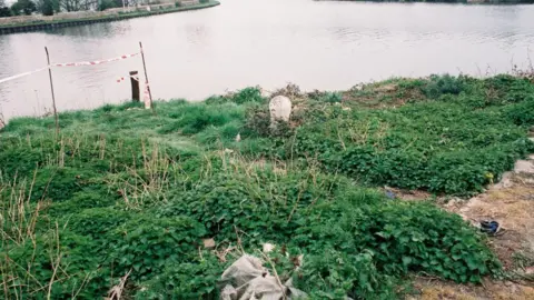 Gloucestershire Police A dated image from the 1990s of green reeds and undergrowth by the Sharpness canal and red and white police tape cordoning part of it off.