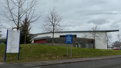 A grey and white hospital building on an overcast grey day