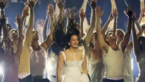 Reuters Rosalia flicks her hair up while performing during the Brit Awards backed by dancers with their hands in the air