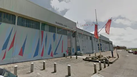 Google The Calshot Activity Centre - a large grey hanger with red, green and blue triangle on the walls