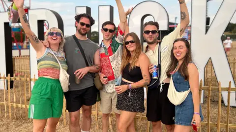 A group of revellers smiling standing in front of a large Truck sign.