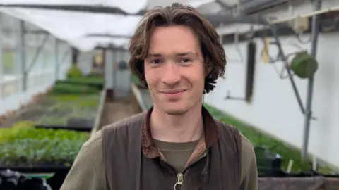 BBC Harrison Fannon from Cowley smiling for a picture in a greenhouse.