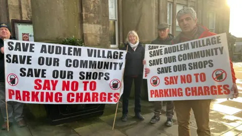 Protestors outside Macclesfield town hall. They are holding signs saying no to parking charges in Audlem.