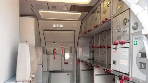 Getty Images The galley on a plane with store cupboards and an emergency exit