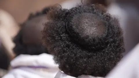 Amensisa Ifa / BBC A circle is shaved into the back of a young man's hair.