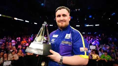 Zac Goodwin/PA Wire Luke Littler holding the Premier League Darts trophy