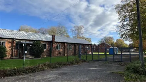 A red brick building behind a fence. 