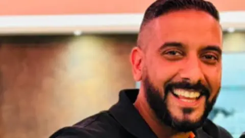 Family Handout Image of Gurvinder, he is smiling and has dark hair and a dark beard