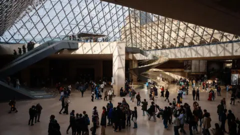 Getty Images A view of the hall of the Louvre under the glass pyramid with lots of people