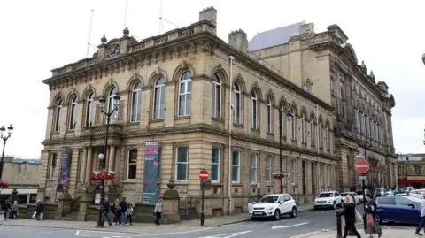 LDRS A large stone building has several large arched windows.
