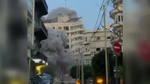 A building collapses in a cloud of dust