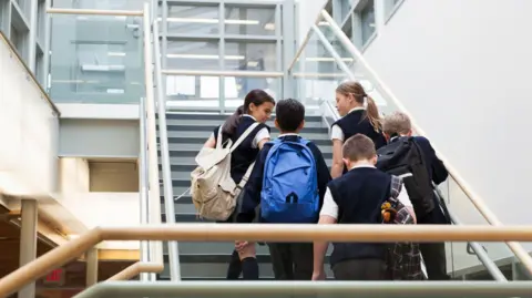 Stock image of five school pupils walking up some stairs