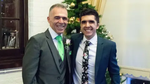 Family handout An older man and a younger man both in suits and ties standing in front of a Christmas tree