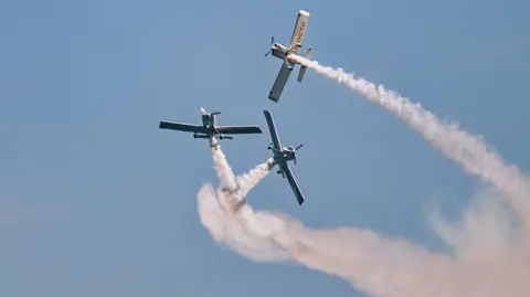 Three planes circle dramatically in the sky