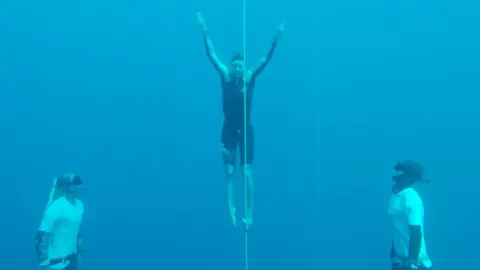 Woman underwater with two other divers