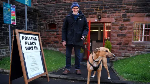 PA Media A voter and his dog at a Glasgow polling station