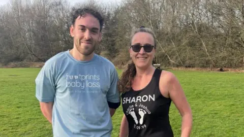 Sharon Darke A young man with brown hiar next to a woman smile at the camera in running gear.