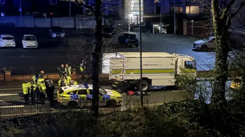 Police officers gather behind a bomb squad van on a street in Chester city centre.