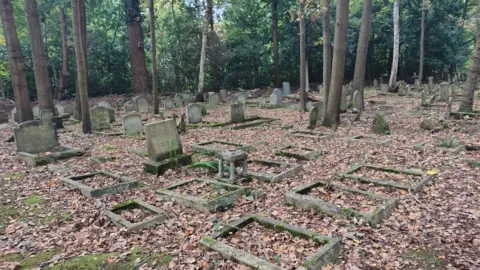 A graveyard. It is covered in fallen, autumnal leaves. 