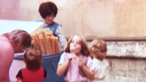 Ognissanti family Lina Ognissanti selling ice creams to children in Bedford in the 1970s. On her small blue push-along truck she has big towers of wafer cones.