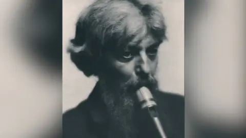 Dolmetsch Family A black and white image of a man playing a recorder