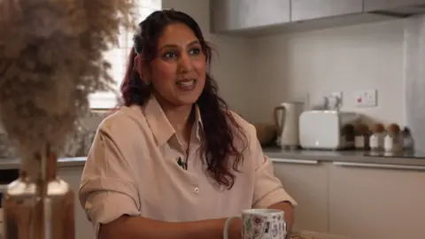 Jasmin Bashir pictured in her kitchen. She has black and dyed red hair.