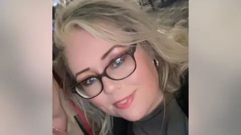 Kimberley Dyson Kimberley Dyson in a cropped selfie image. She is smiling. She has blond hair, brown eyebrows, eyeshadow and dark glasses. She wears a thin gold chain, gold hoop earrings, and a nose ring.