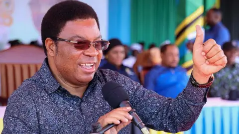 A close up of Kassim Majaliwa wearing glasses and a floral shirt 