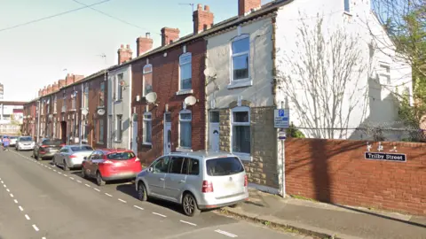 Google A row of terrace houses with cars parked outside.