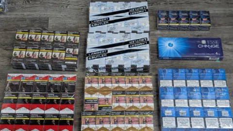 Hampshire & Isle of Wight Constabulary A haul of illicit cigarettes and tobacco on a wooden surface