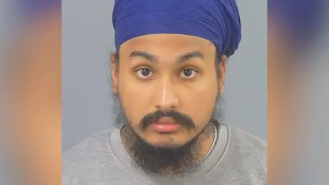 Police handout Custody photo of Vickrum Digwa, a man with a beard, a grey jumper and a purple turban looking to the camera.