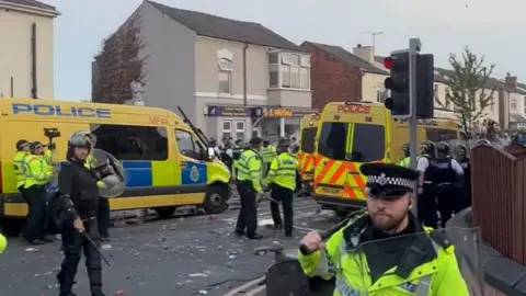 PA Media Police officers and riot vans are dealing with rioters in Southport 